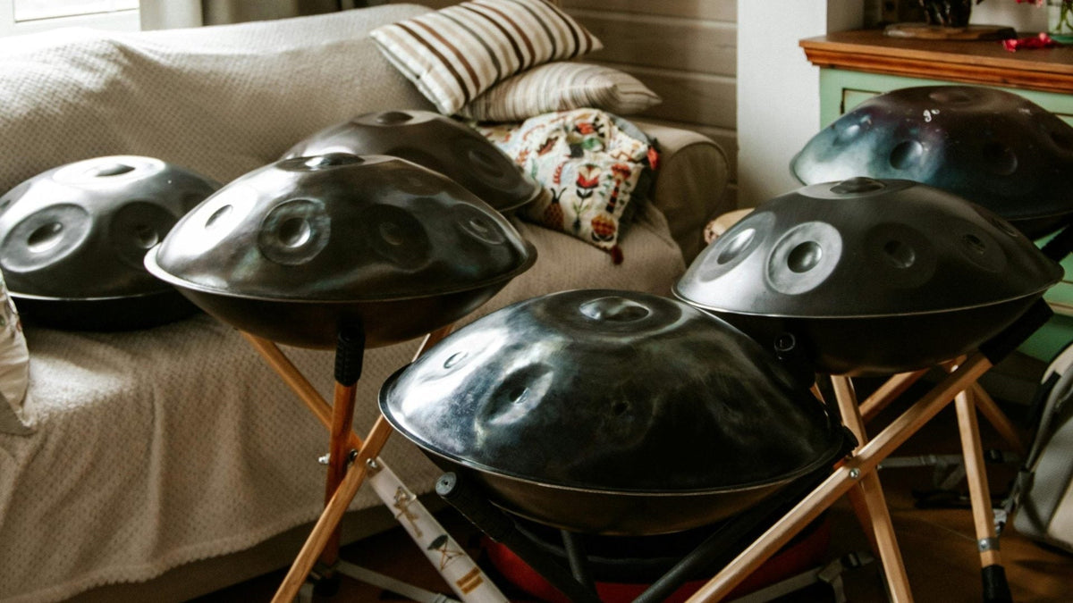 Several handpans lying side by side on cushions and wooden stands